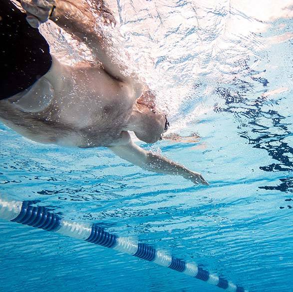 Mann med stomipose som svømmer i basseng