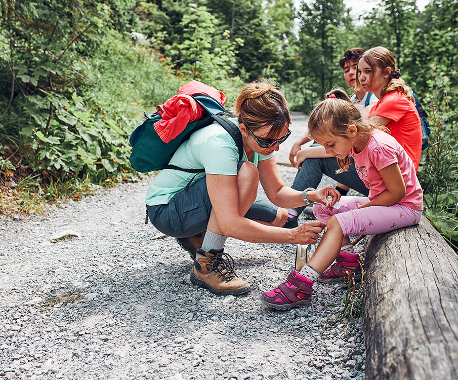 Dame som setter på plaster på kneet til jente